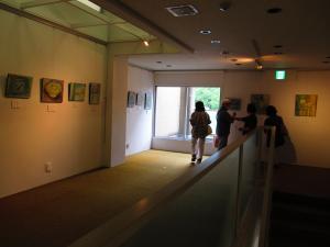 2階展示　階段を上がったところで絵の説明を受ける来館者さん