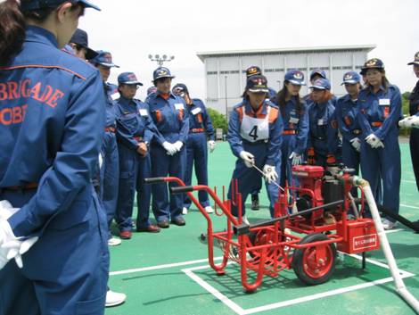 小型ポンプのエンジン始動の方法を学ぶ女性消防団員の画像