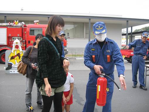 消火器の使い方を教える消防団員の画像